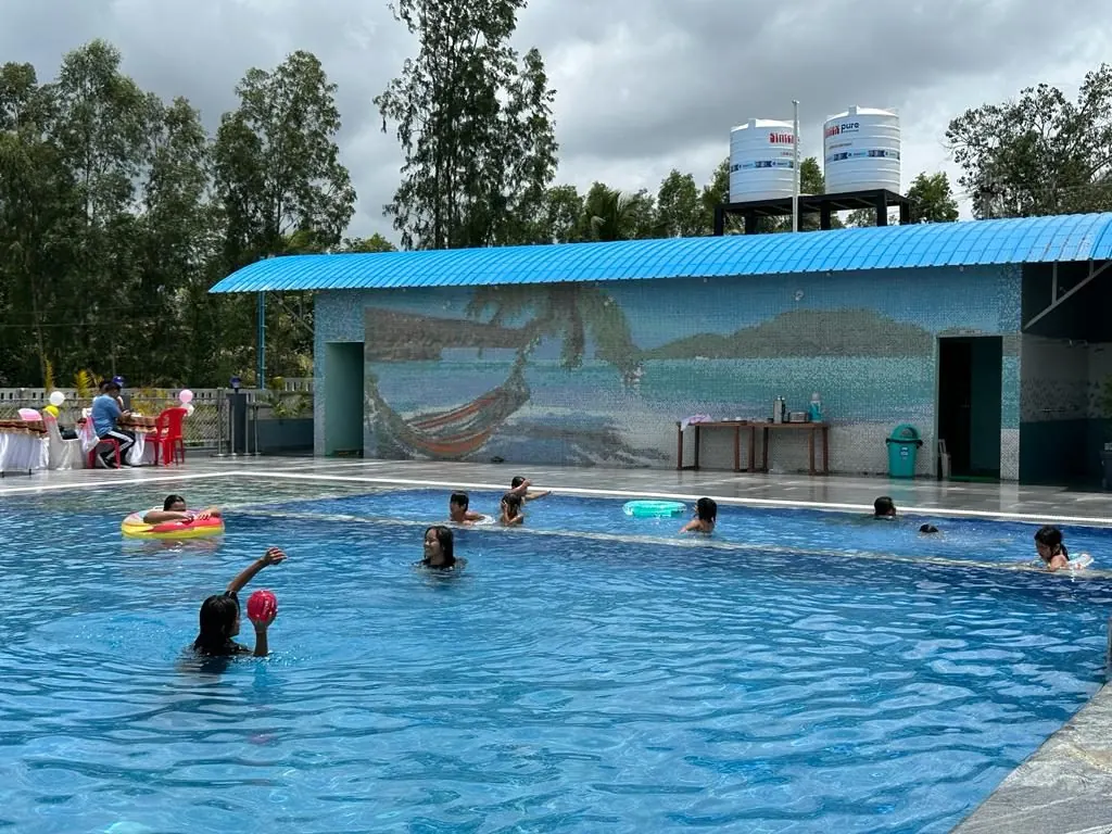 Guests swimming in the pool at FTCI Bylakuppe